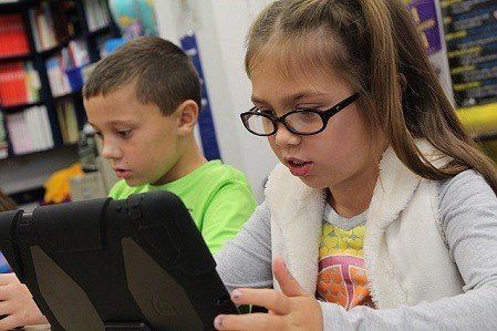 A boy and a girl are using a tablet computer in a classroom.